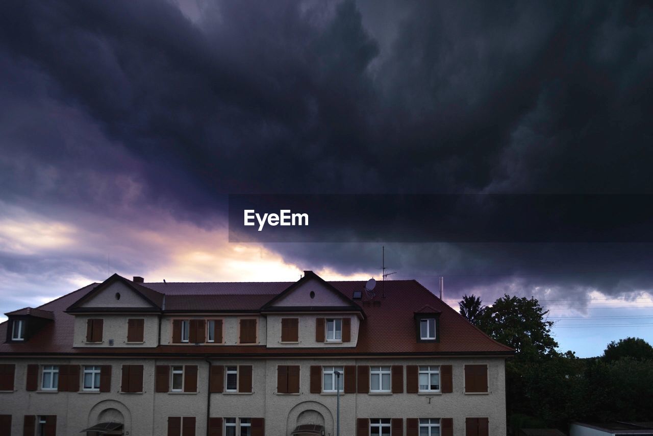 LOW ANGLE VIEW OF BUILDING AGAINST DRAMATIC SKY