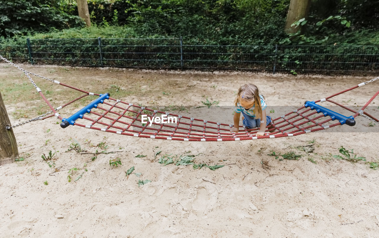 High angle view of girl sitting on hammock outdoors