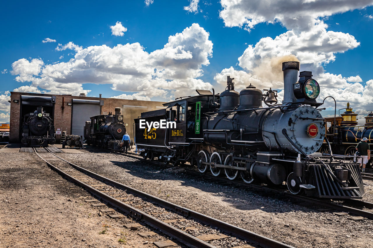 rail transportation, railroad track, track, transportation, train, mode of transportation, sky, cloud, locomotive, vehicle, railway, transport, public transportation, land vehicle, nature, steam train, travel, no people, freight transportation, day, sunlight, business, outdoors, railroad station, wheel, station, architecture