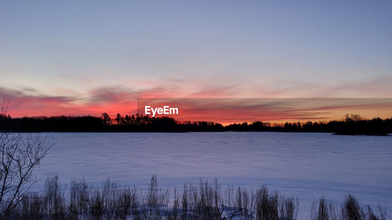 sky, beauty in nature, scenics - nature, reflection, sunset, tranquility, dawn, tree, tranquil scene, plant, water, winter, nature, evening, cloud, landscape, environment, cold temperature, snow, lake, no people, non-urban scene, land, idyllic, forest, outdoors, frozen, horizon, twilight, silhouette, blue, coniferous tree, sunlight, woodland, afterglow, pine tree, remote, pinaceae, orange color