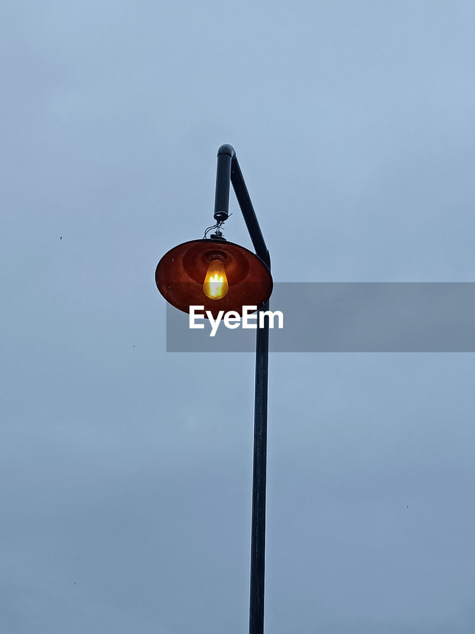 Low angle view of illuminated light bulb against sky