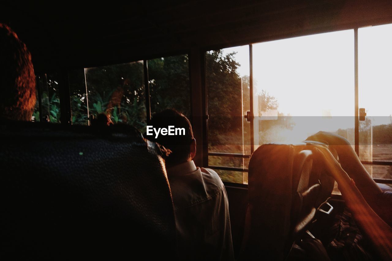 Man sitting in bus during sunset