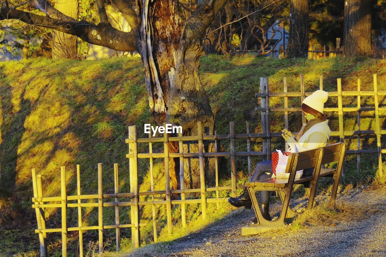 Side view of woman sitting on bench at park