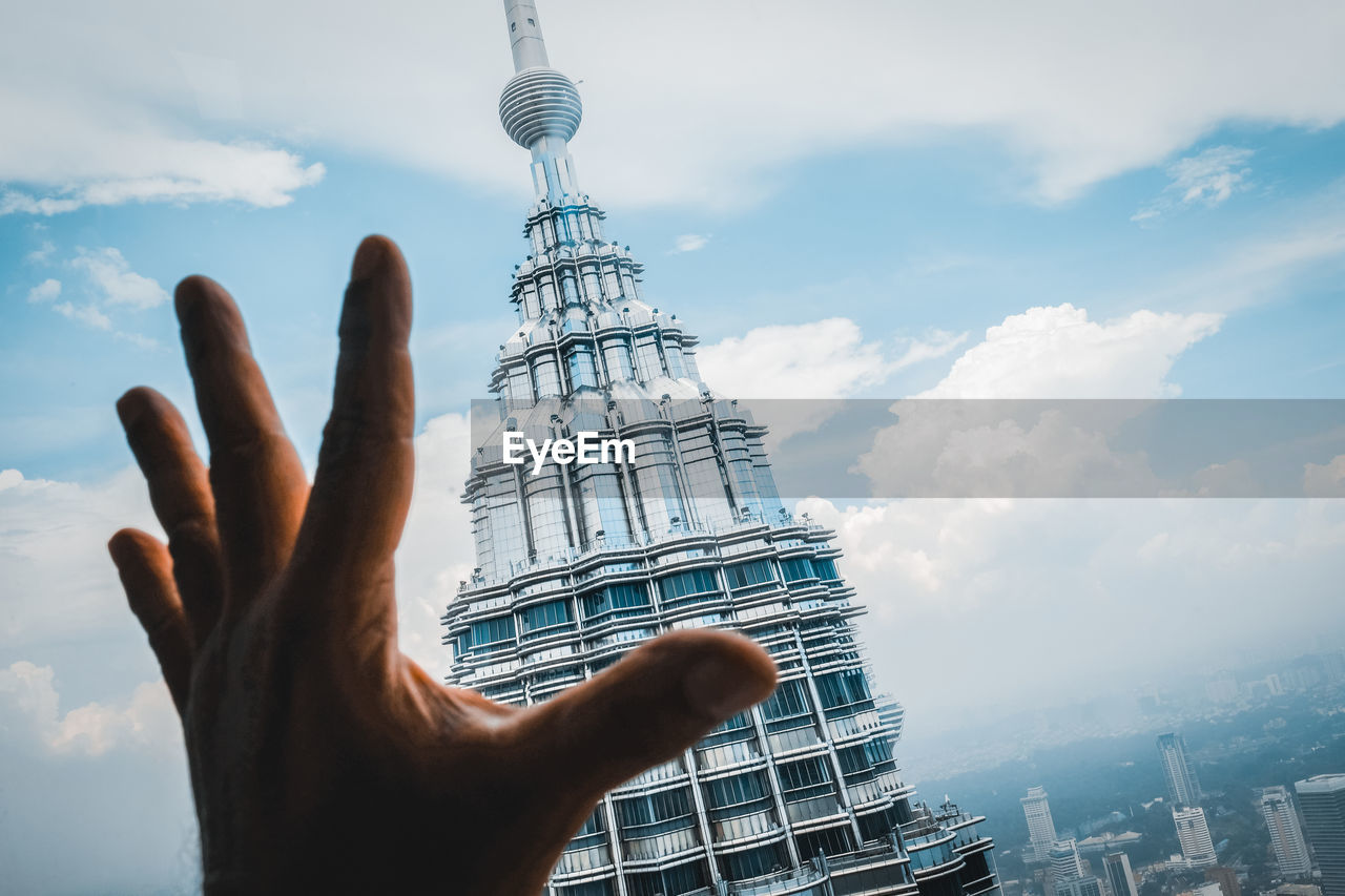 Cropped image of person against modern building in city