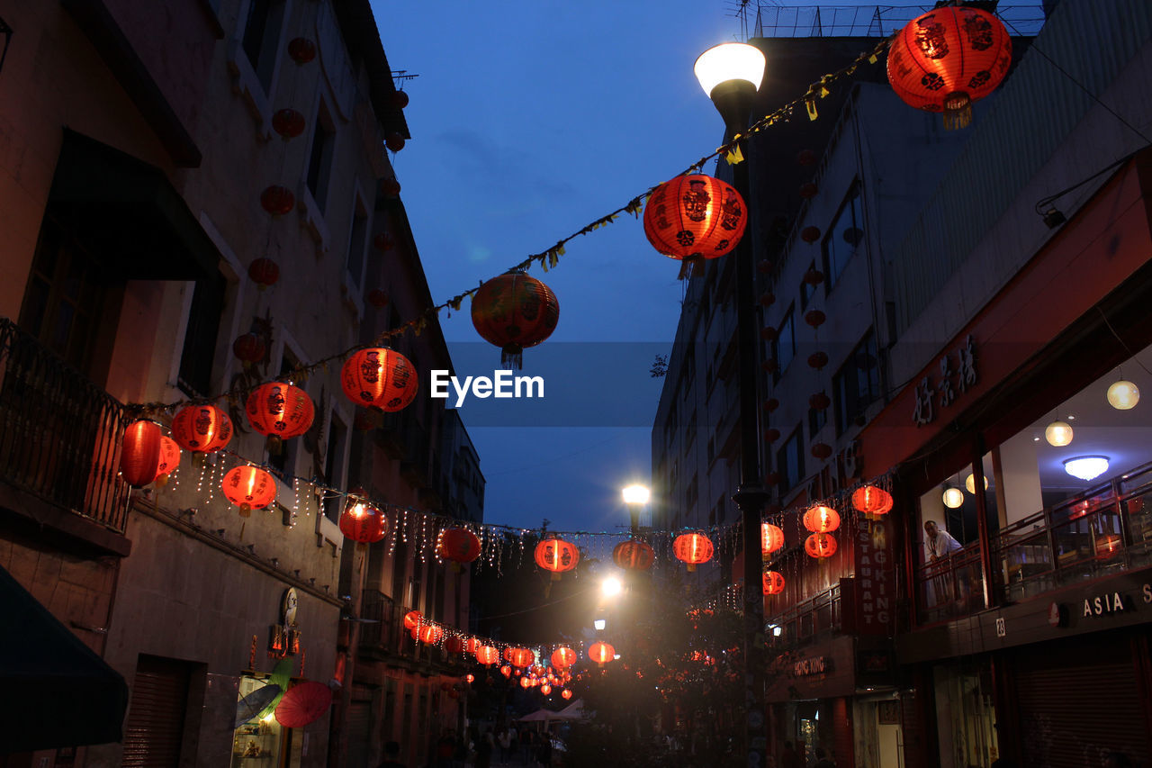 LOW ANGLE VIEW OF ILLUMINATED LANTERNS HANGING AGAINST SKY