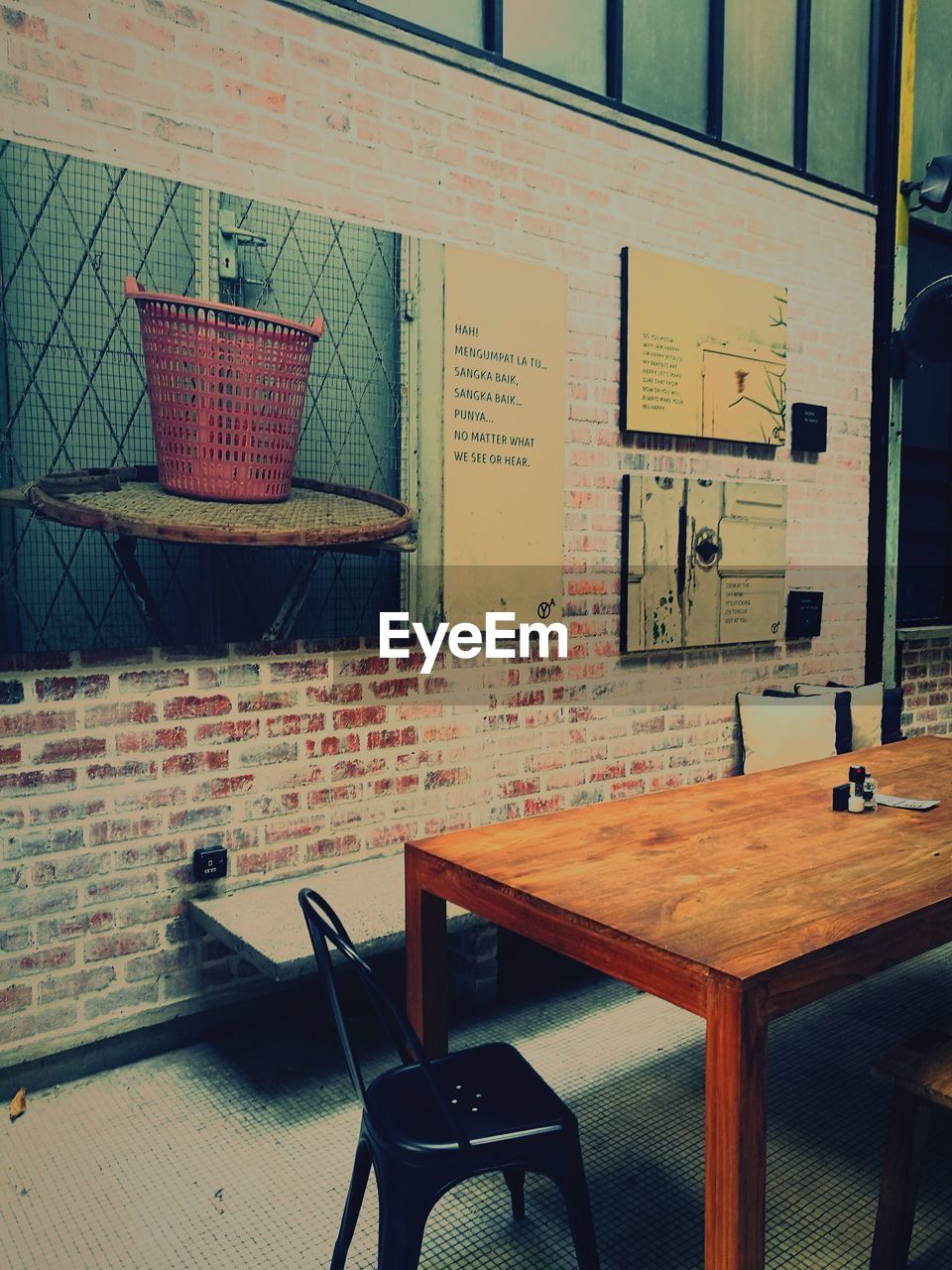 EMPTY CHAIRS AND TABLE AGAINST WALL IN CAFE