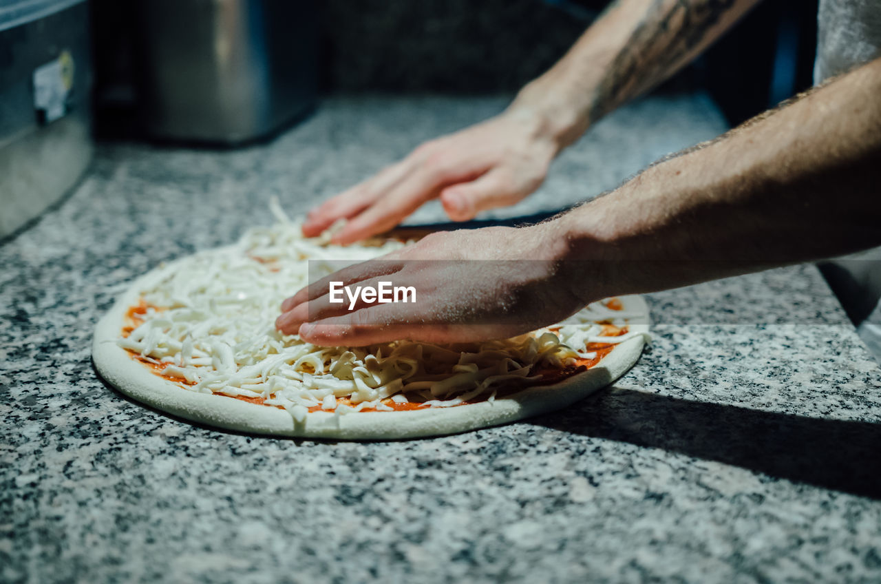 Cropped image of chef preparing pizza at kitchen counter