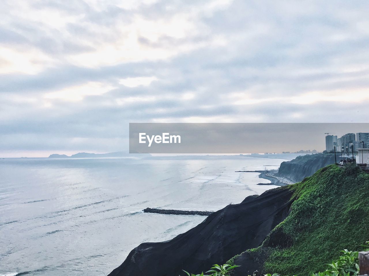 SCENIC VIEW OF BEACH AGAINST CLOUDY SKY