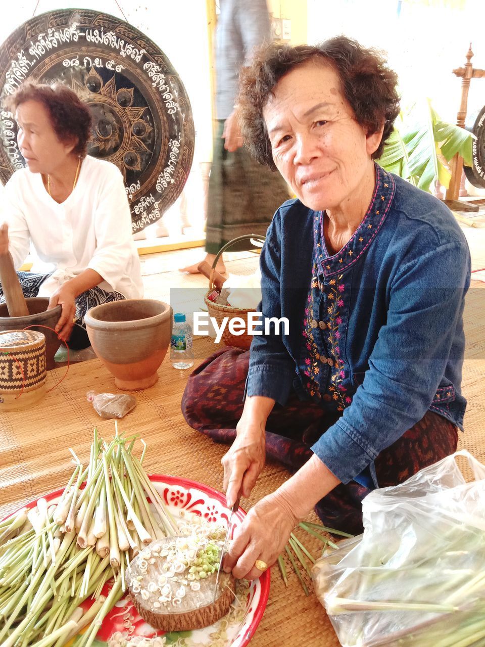 Portrait of mature woman chopping spring onions on floor