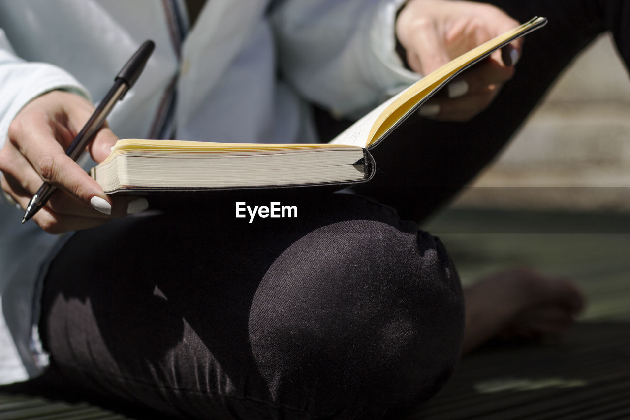 MIDSECTION OF WOMAN READING BOOK