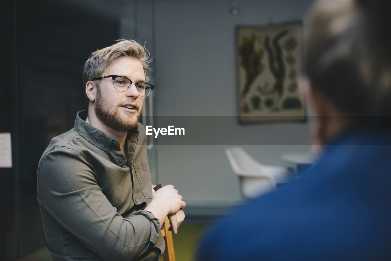 Confident male computer programmer talking to female colleague in office