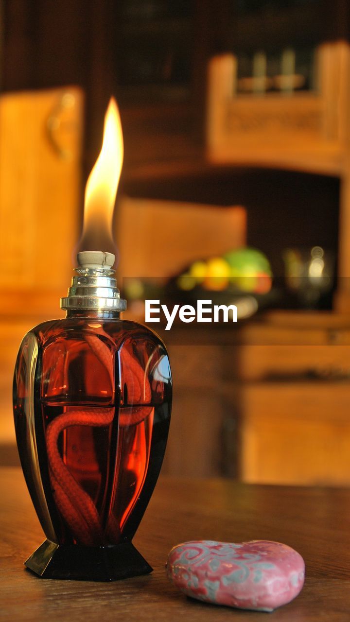 Close-up of burning oil lamp on table at home