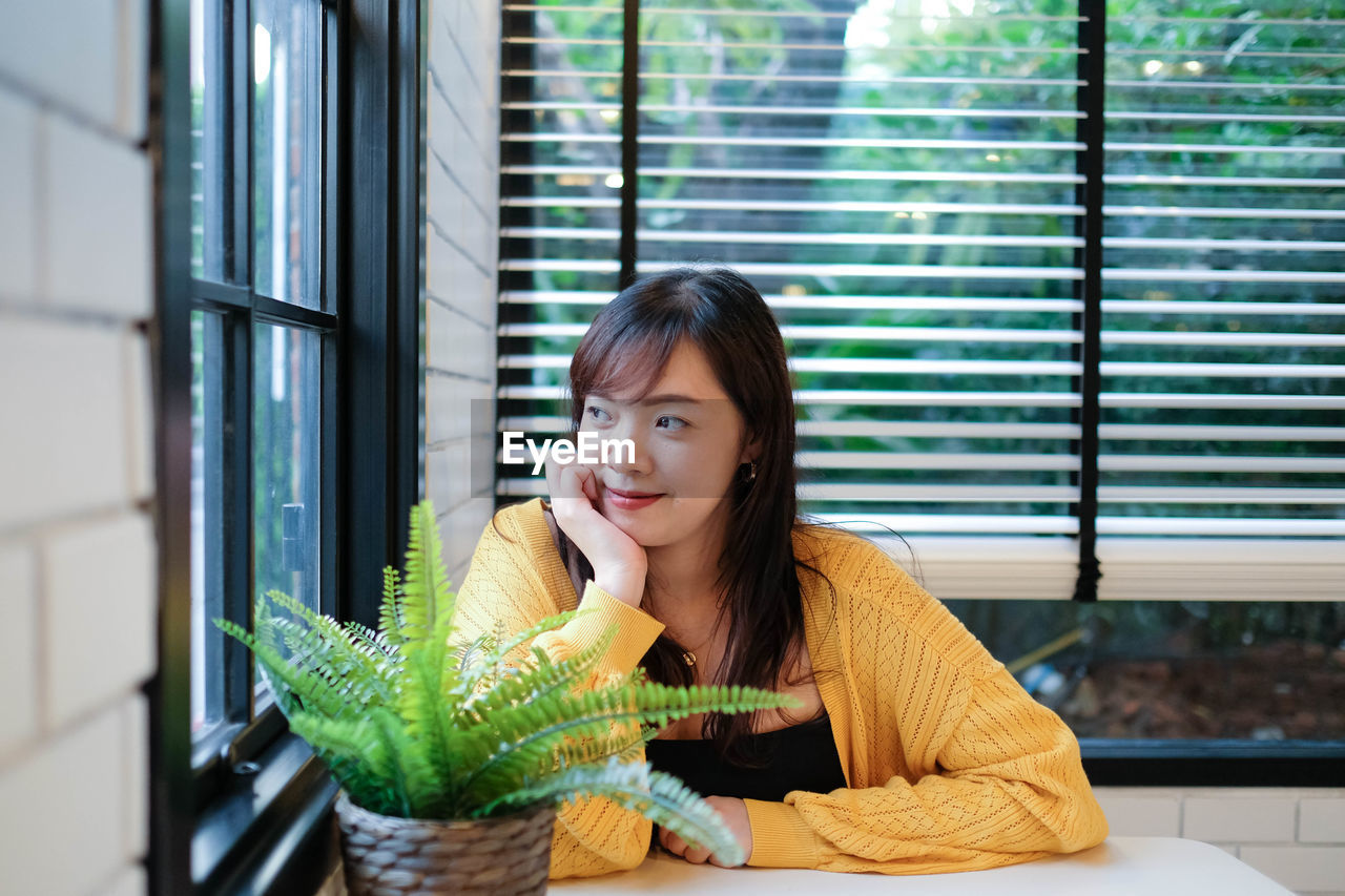 Close up of young pretty asian woman sitting in the cafe feeling relax.