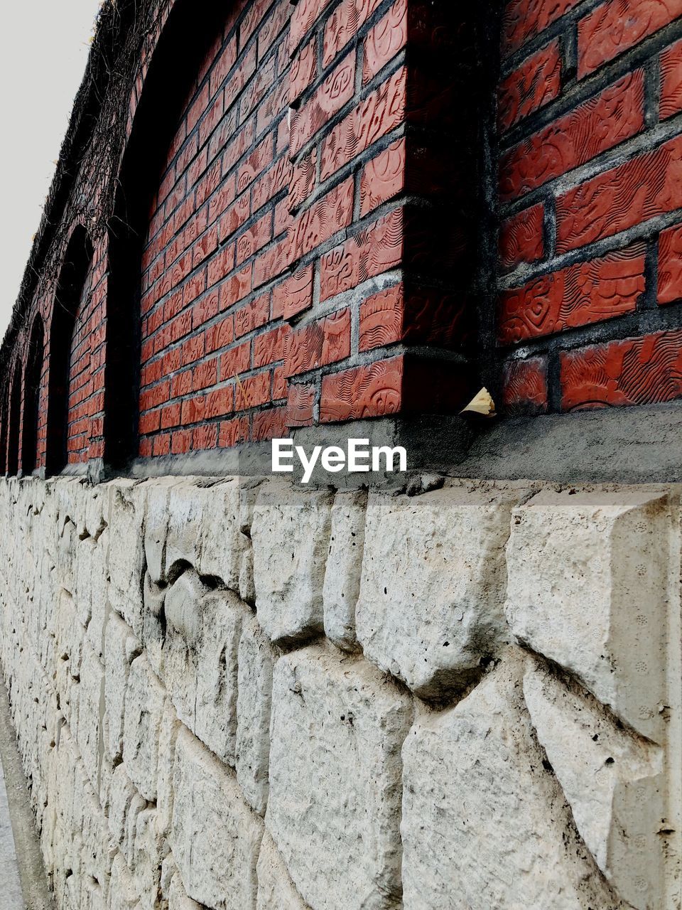 BRICK WALL WITH RED STRUCTURE ON STONE