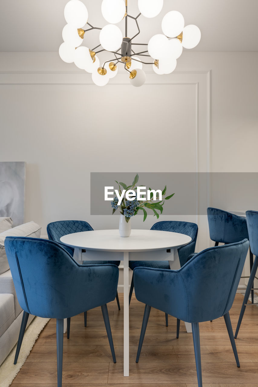 Dining table with blue chairs and large chandelier in the interior