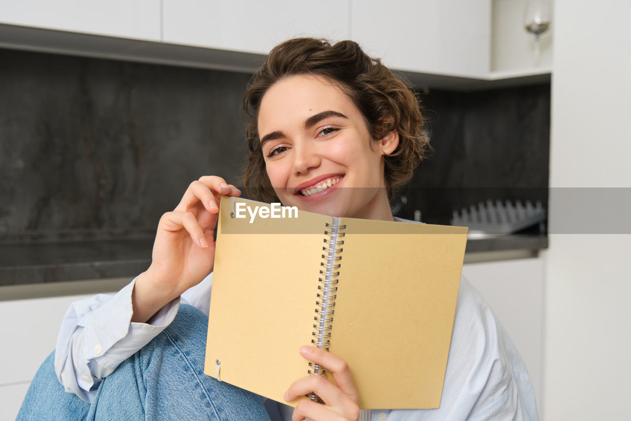 portrait of young woman reading book at home