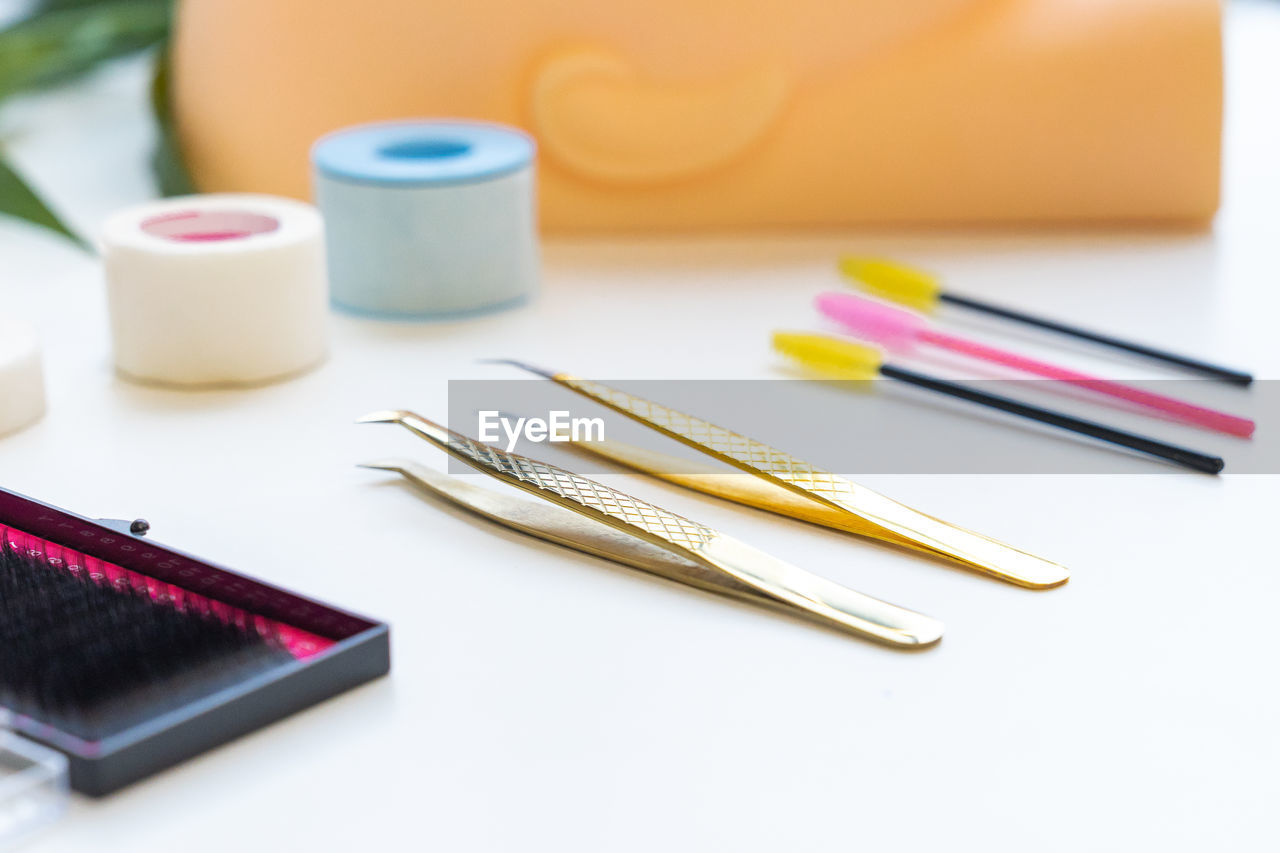 Close-up of false eyelashes with tweezers and curlers on table