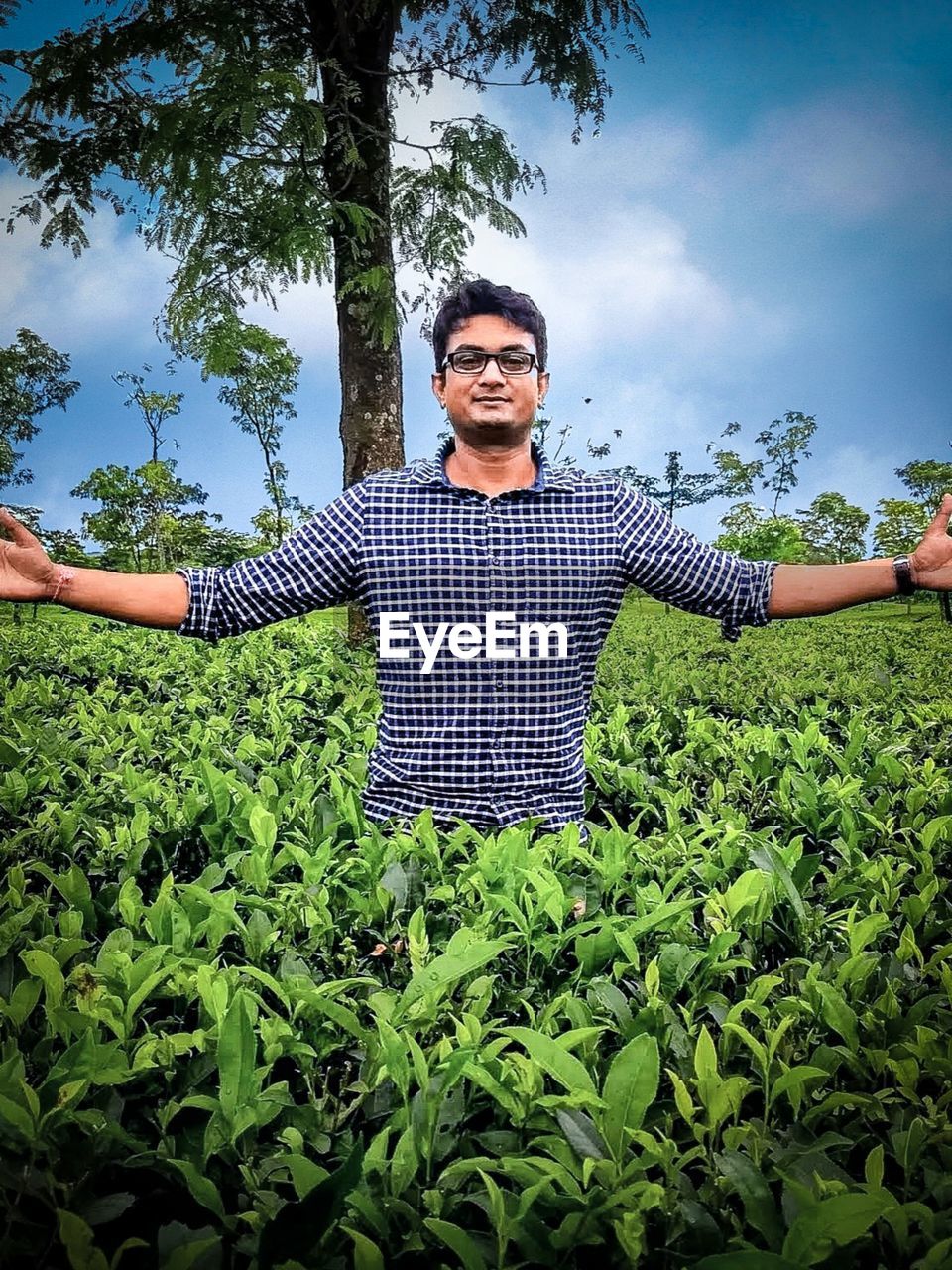 PORTRAIT OF YOUNG MAN STANDING BY TREE