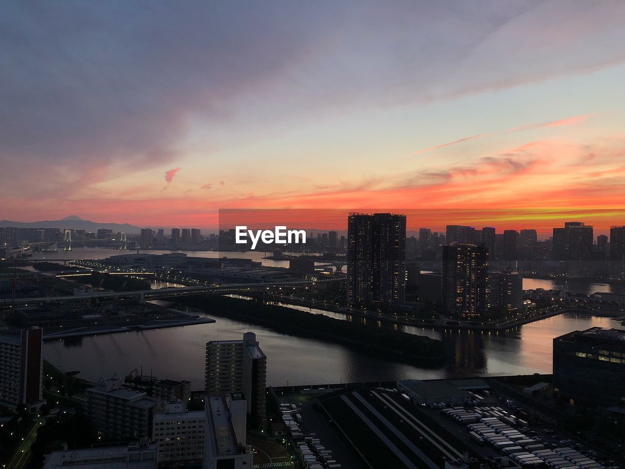 High angle view of river by buildings against sky during sunset