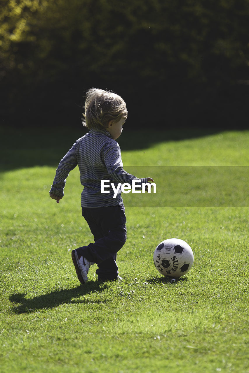 Full length of boy playing soccer on field