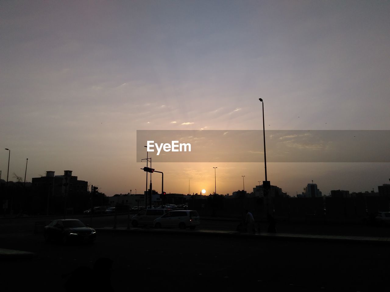 VEHICLES ON ROAD AGAINST SKY DURING SUNSET