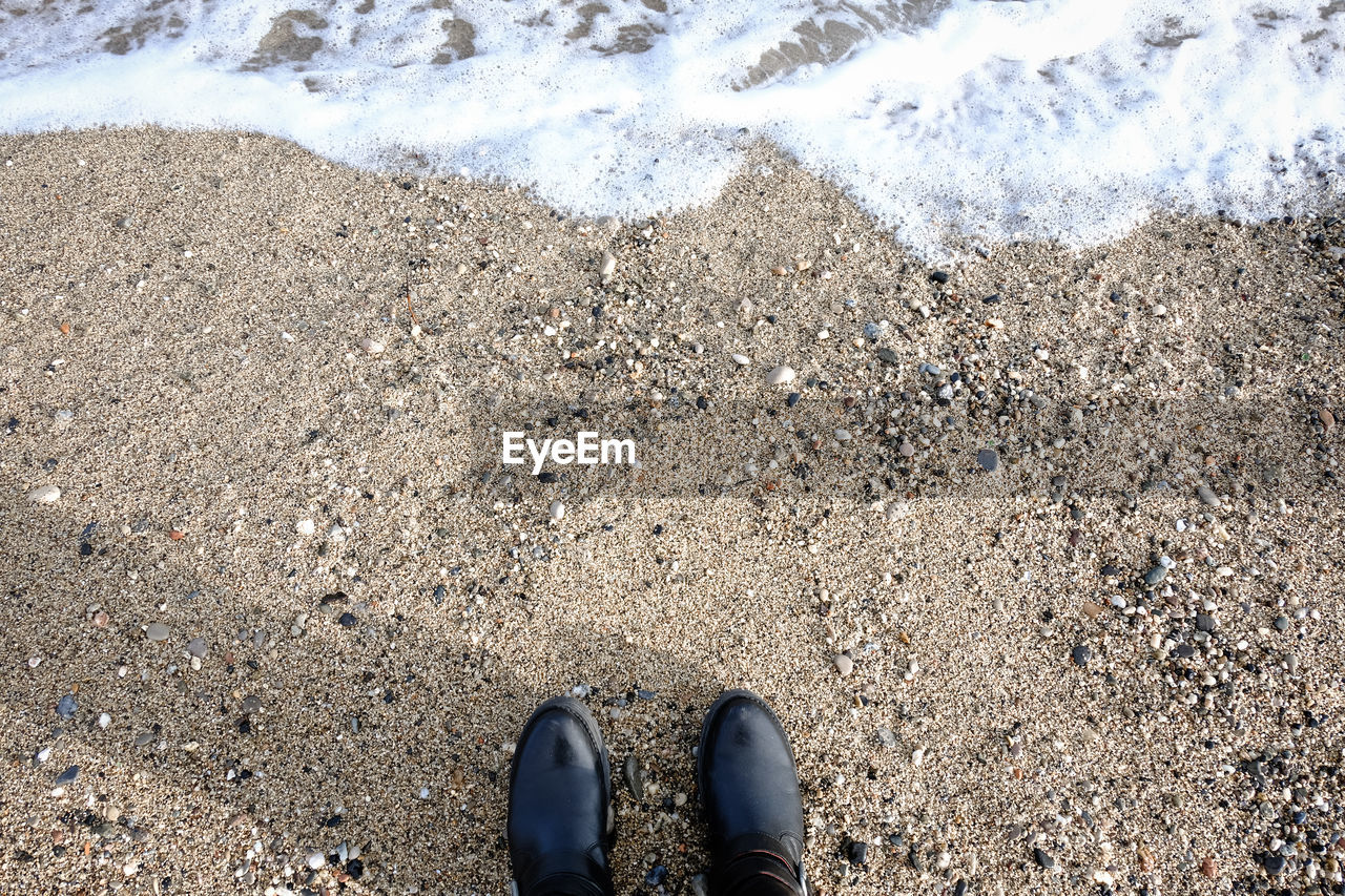 LOW SECTION OF PERSON STANDING ON SHORE