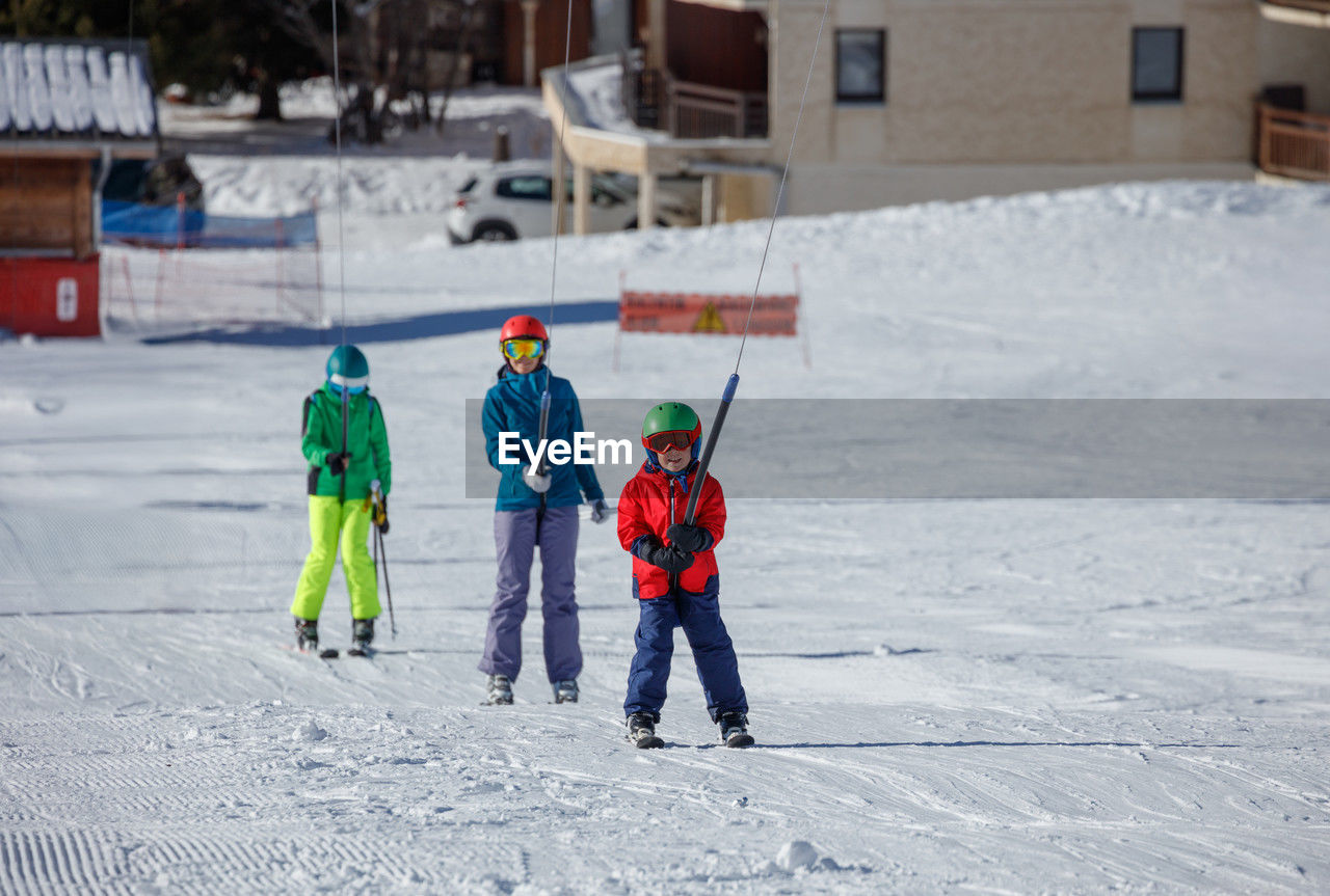winter, cold temperature, snow, child, childhood, men, warm clothing, clothing, skiing, full length, sports, nordic skiing, winter sports, togetherness, family, group of people, day, sports equipment, female, footwear, nature, leisure activity, architecture, fun, women, ski, adult, helmet, small group of people, hat, headwear, outdoors, ice, frozen, enjoyment