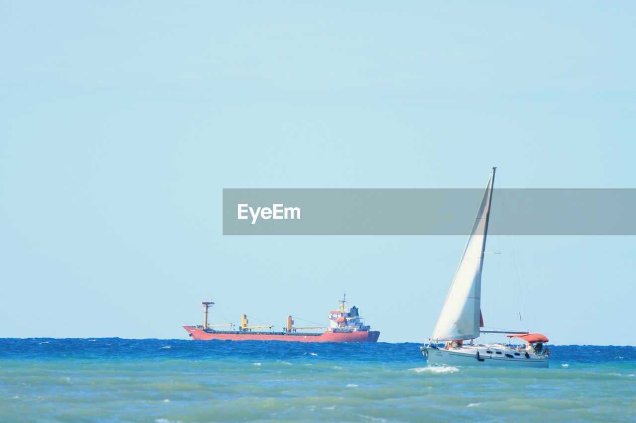 Sailboat sailing on sea against clear sky