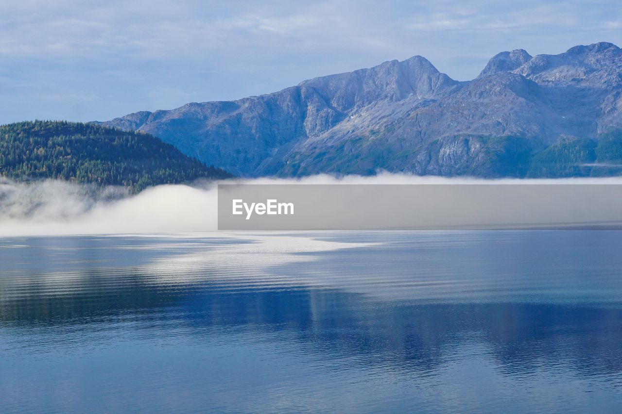 Scenic view of lake by mountains against sky