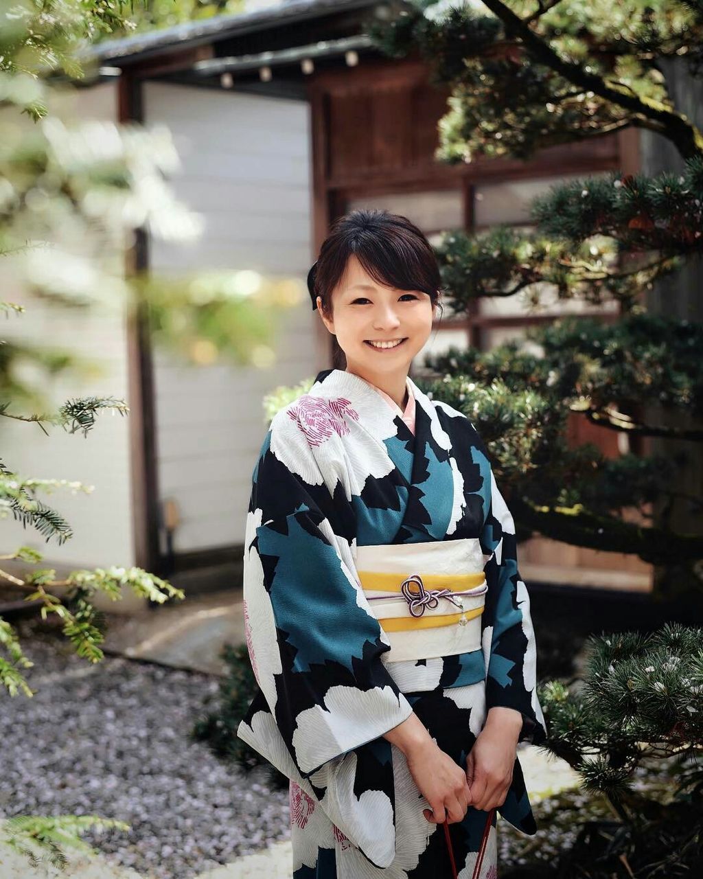 PORTRAIT OF A SMILING YOUNG WOMAN AGAINST BUILDING