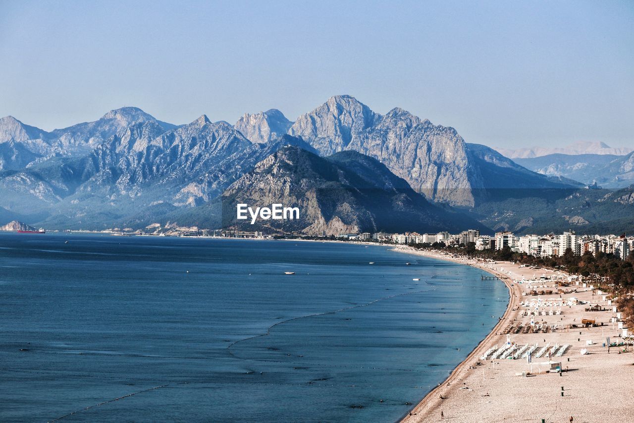 Scenic view of snowcapped mountains by sea against clear sky