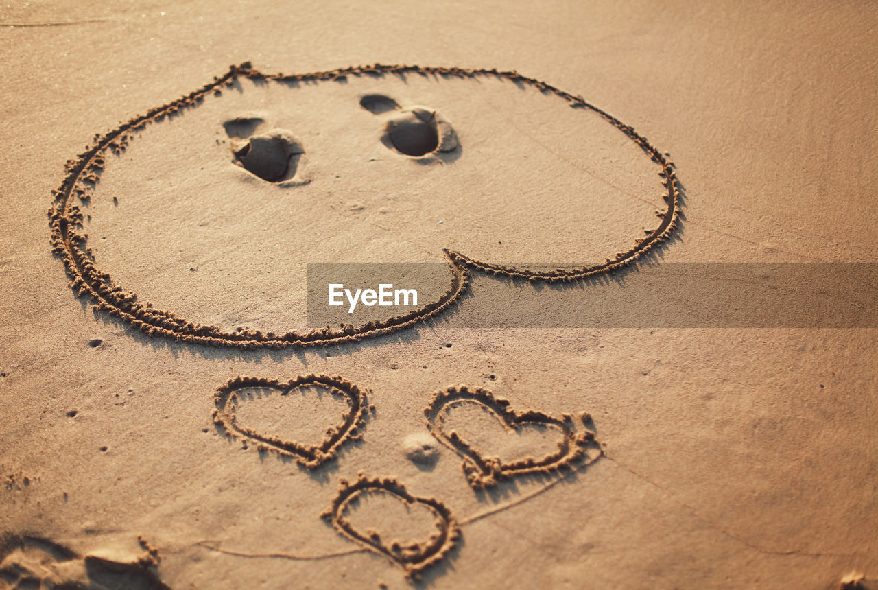 Close-up of heart shape on sand at beach