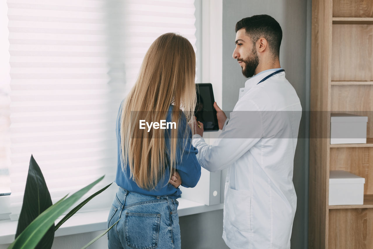 A friendly male doctor of oriental appearance advises the patient, shows information