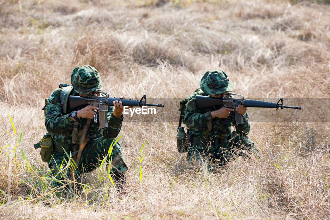Army soldiers shooting with rifle on field