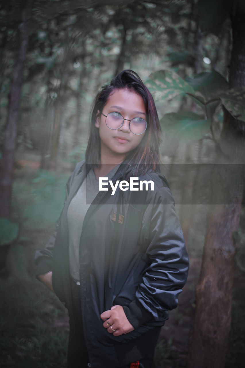 Teenager girl looking away while standing in forest