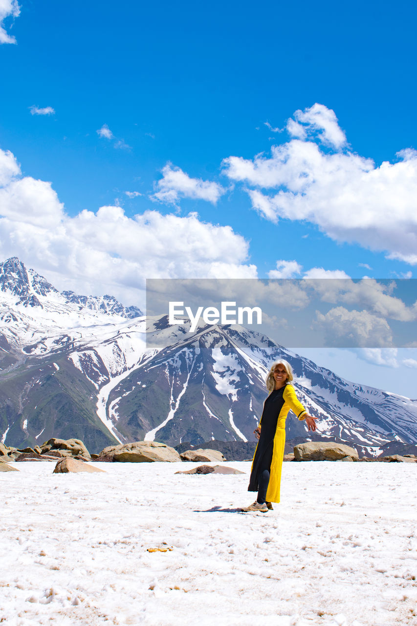 Full length of woman standing on snowcapped mountain