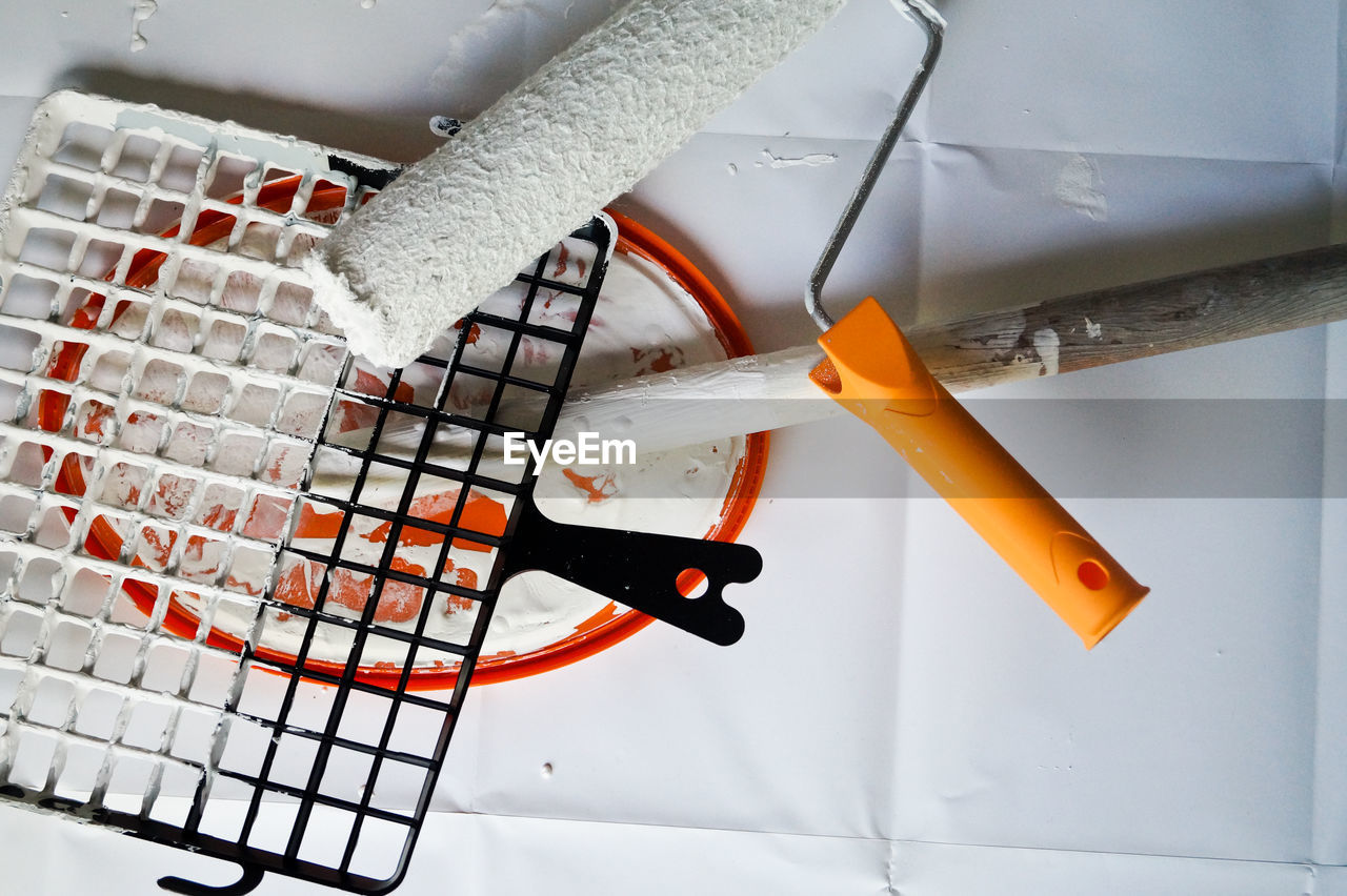 High angle view of metal grate and paint roller on paper