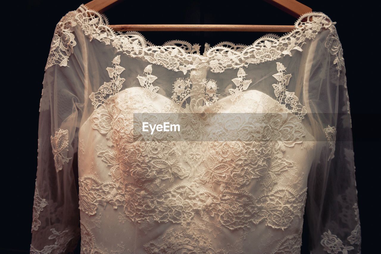 Close-up of wedding dress against black background