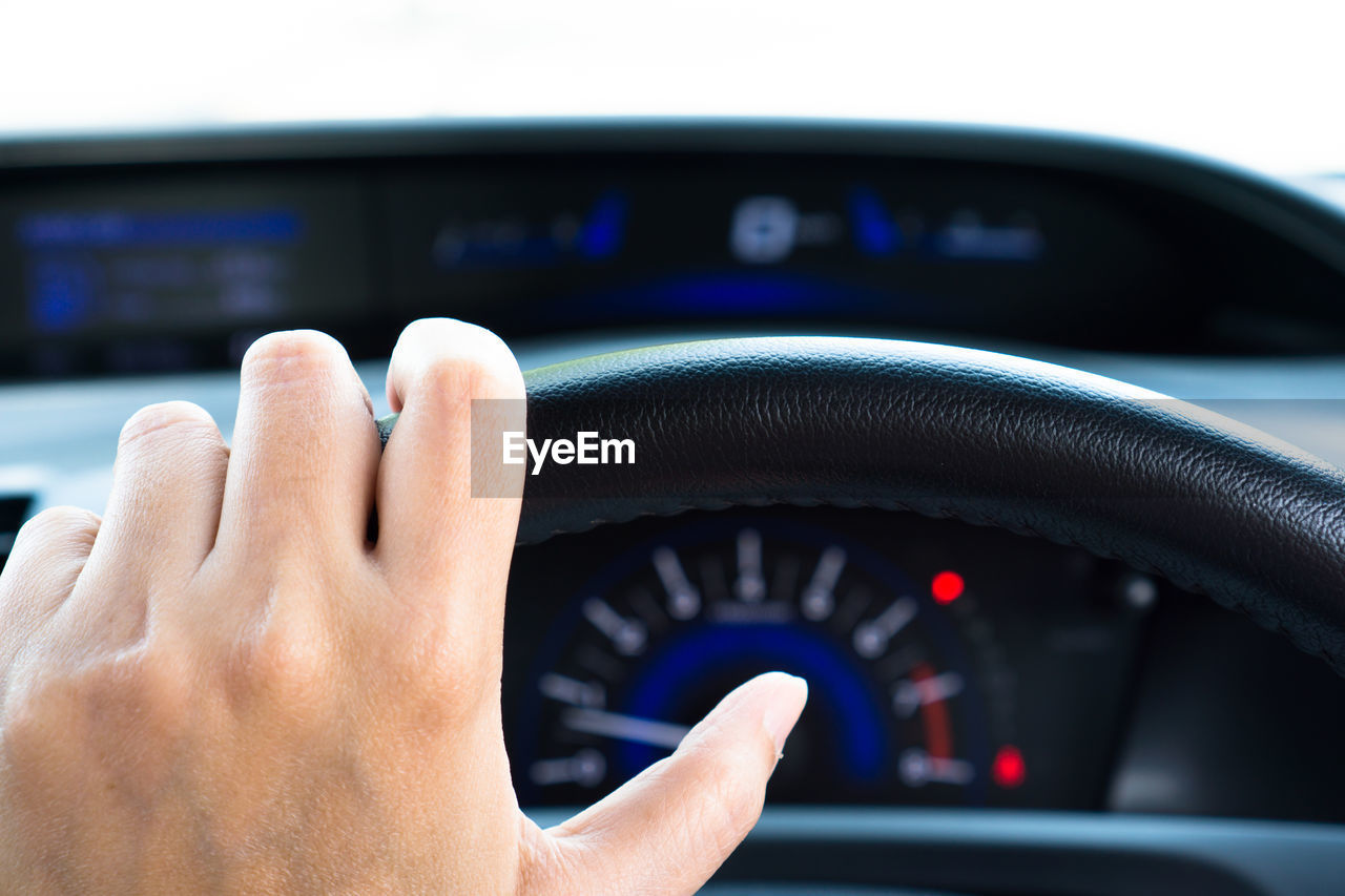Close-up of human hand on steering wheel 