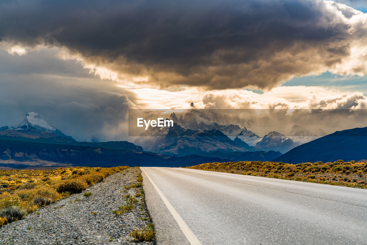 Road leading towards mountains against sky