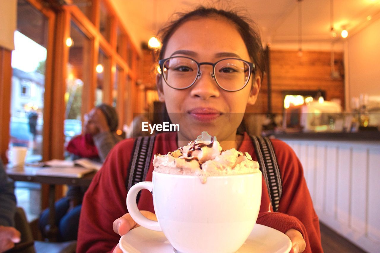 Portrait of woman holding coffee at restaurant