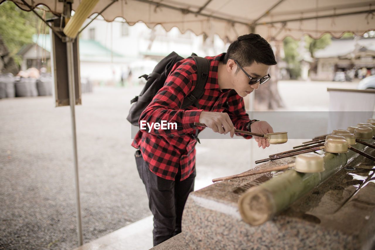 Man pouring water with ladle on hand