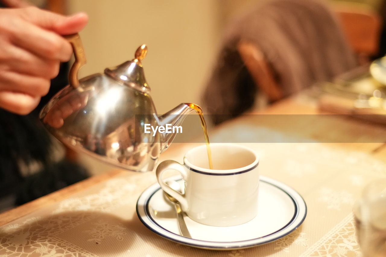 cropped hand of woman using mobile phone on table