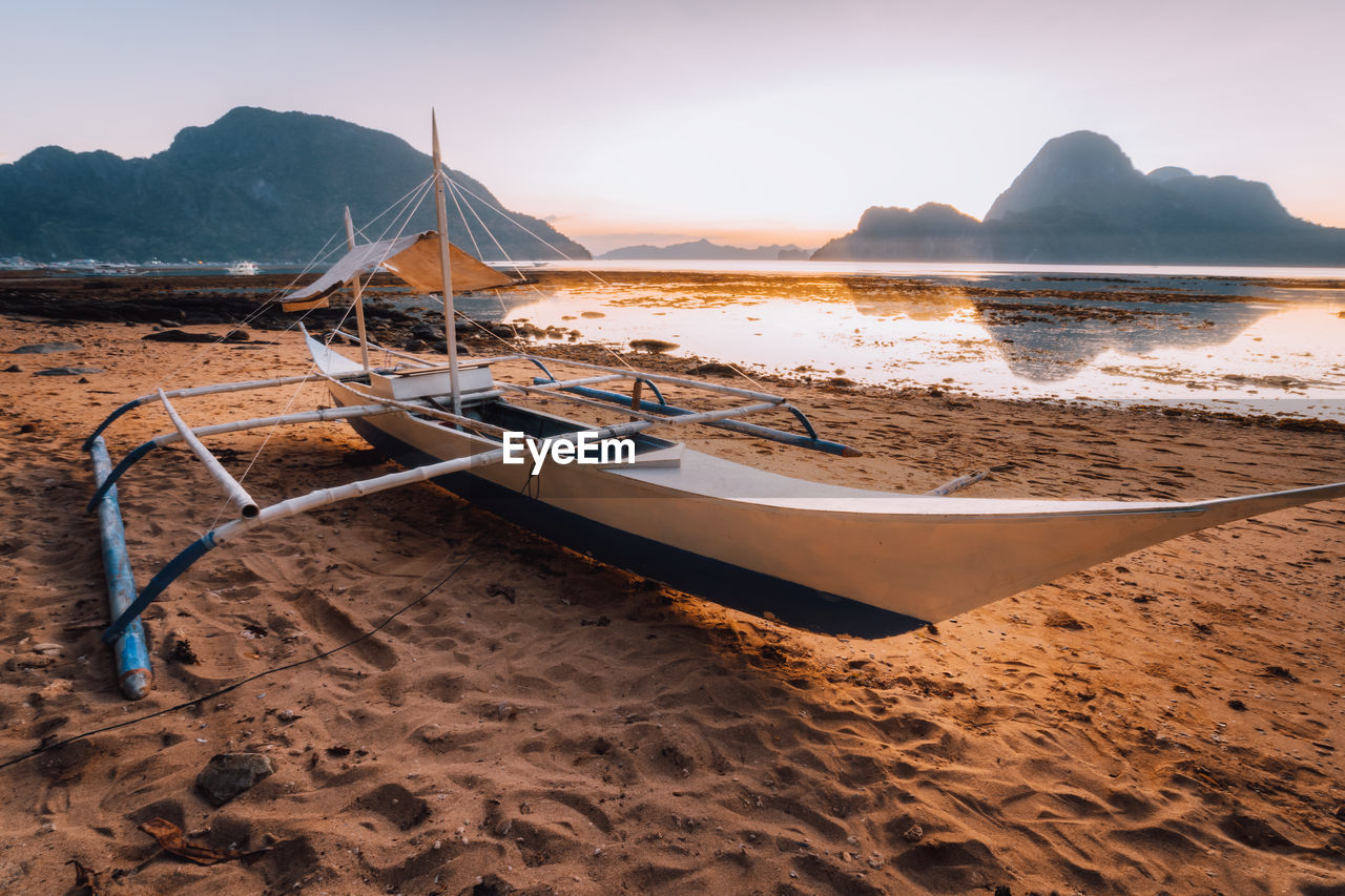 Boat moored at beach against sky