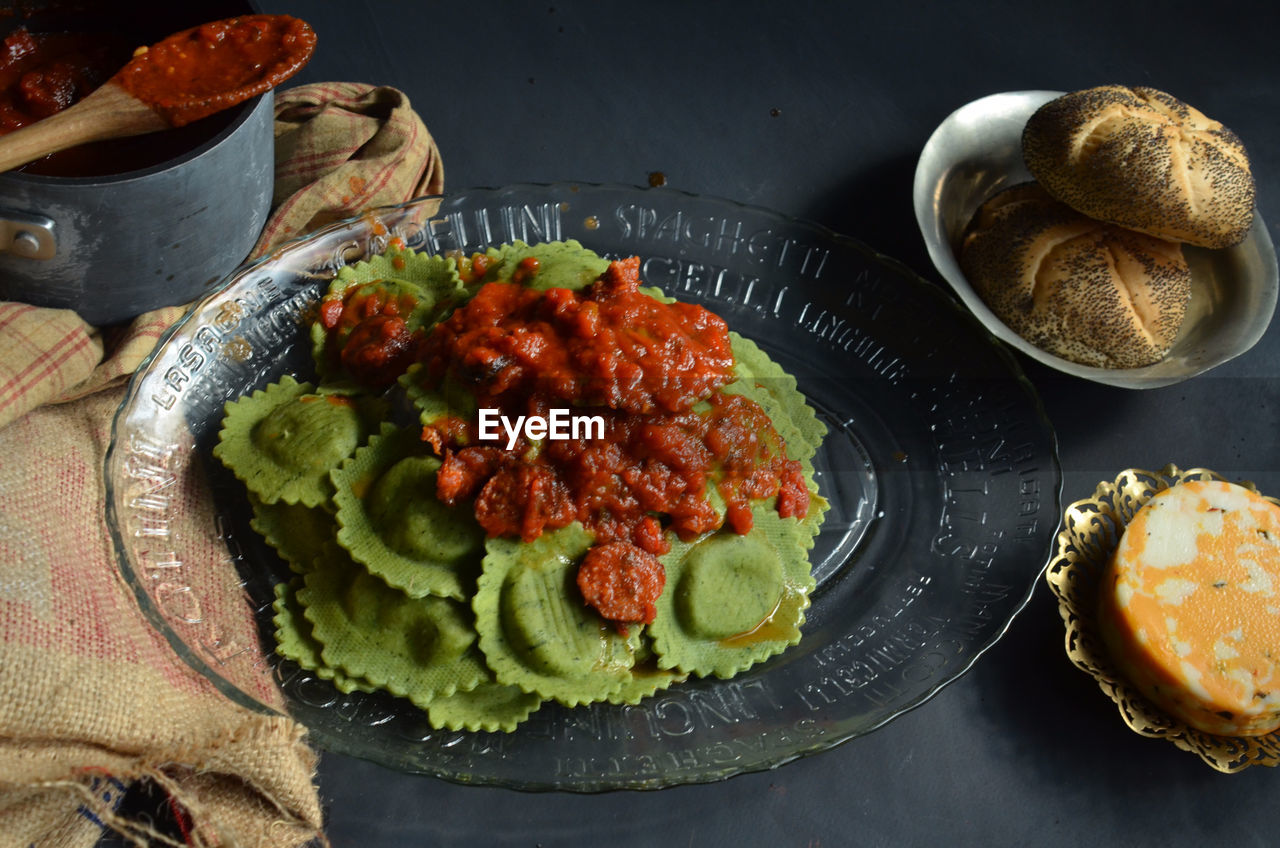 High angle view of spinach ravioli with red marinara sauce in plate on table