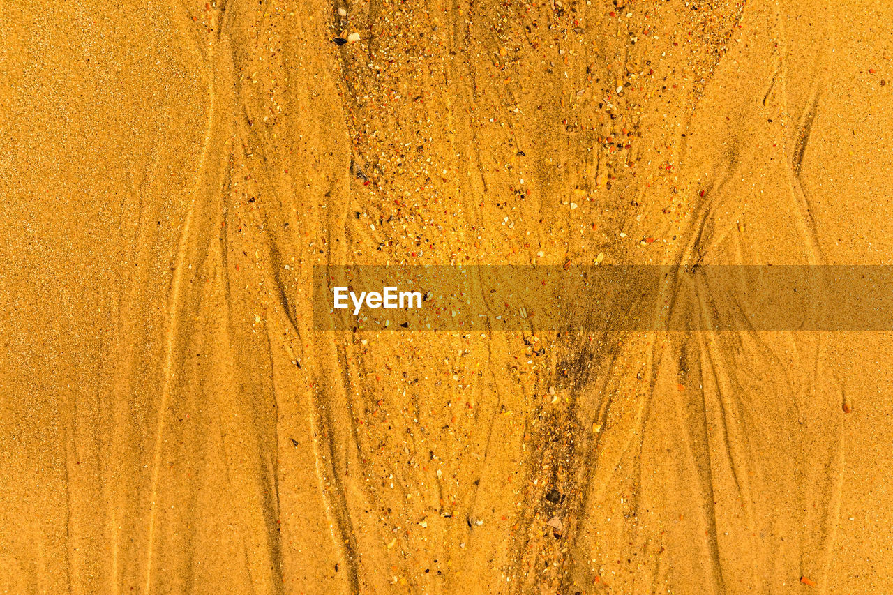 Close-up of sand with tidal ways and shells on the beach, full frame texture