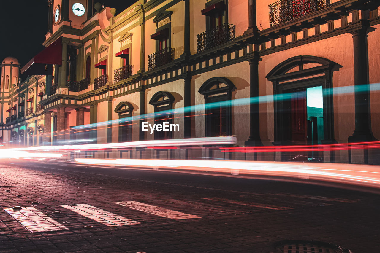 Light trails on street against buildings at night