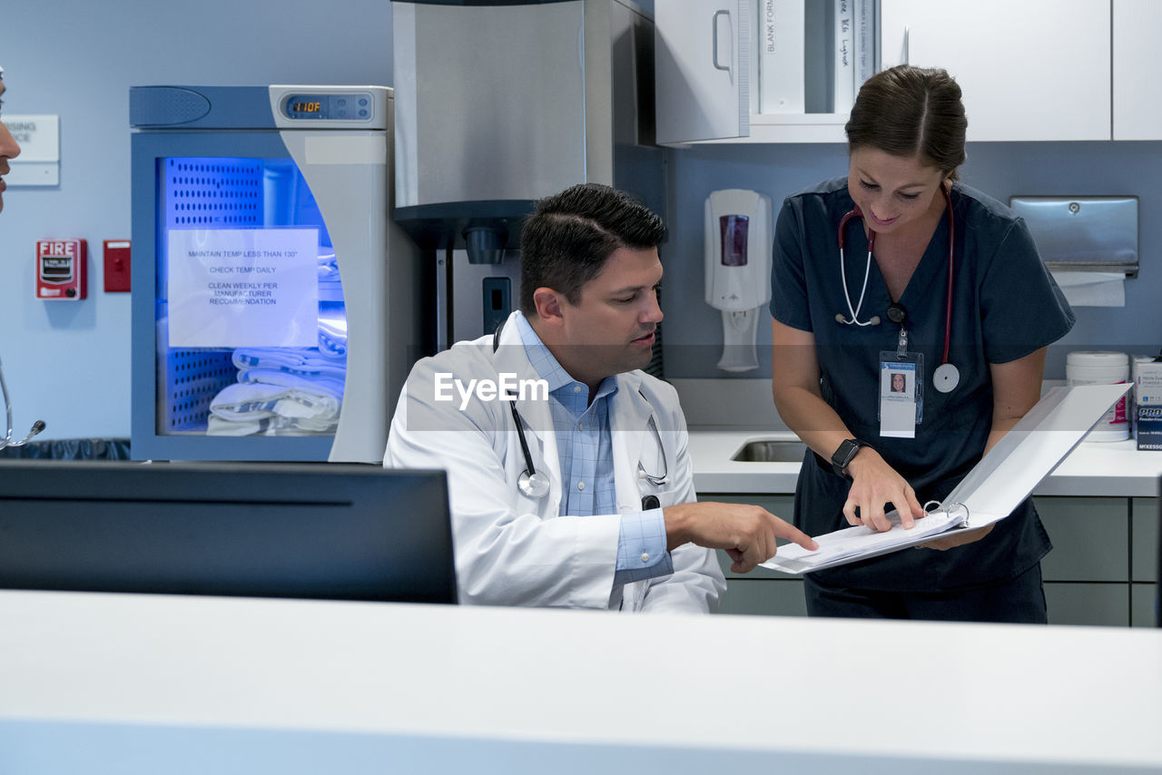 Doctor and nurse reviewing documents at hospital reception