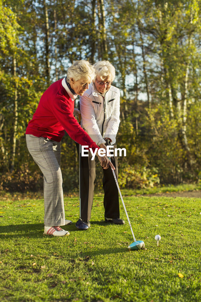 Full length of senior female friends playing golf