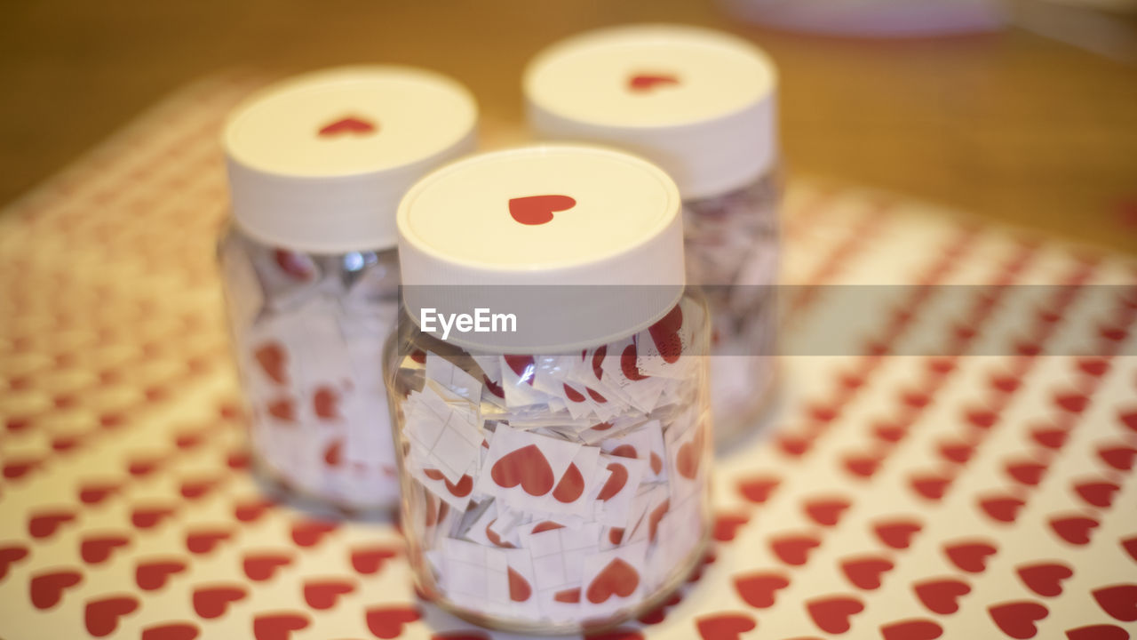 indoors, pink, no people, focus on foreground, pattern, table, lighting, close-up, container, food and drink, checked pattern, tablecloth, food, art, still life, jar